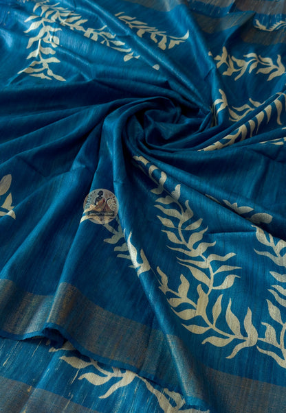Close-up of Ghicha Tussar Silk weave revealing raised natural texture, wild forest silk variation and golden-brown depth — each thread placed by hand, glowing softly in morning light and shimmering under festive diyas