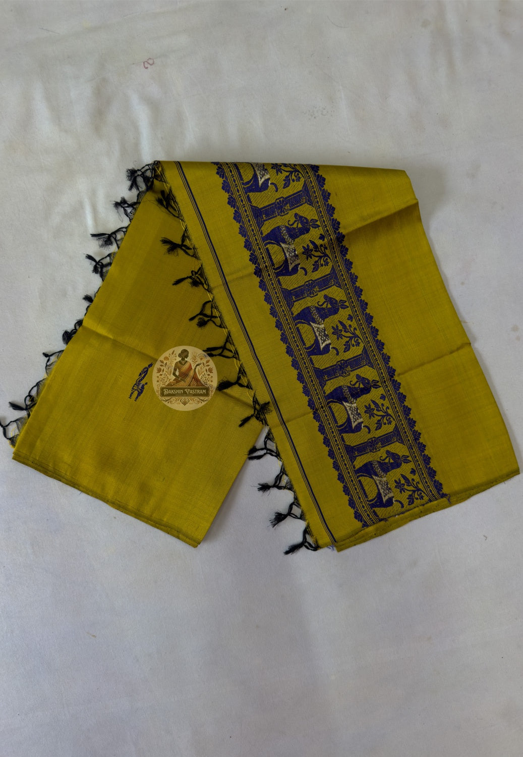 Full flat lay of handwoven Baluchari silk stole in mustard yellow – complete view of woven buti body, indigo narrative border and black silk tassel fringe, Bishnupur weave