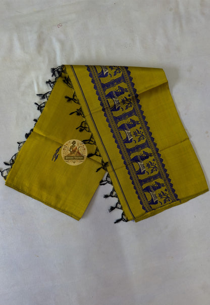 Full flat lay of handwoven Baluchari silk stole in mustard yellow – complete view of woven buti body, indigo narrative border and black silk tassel fringe, Bishnupur weave