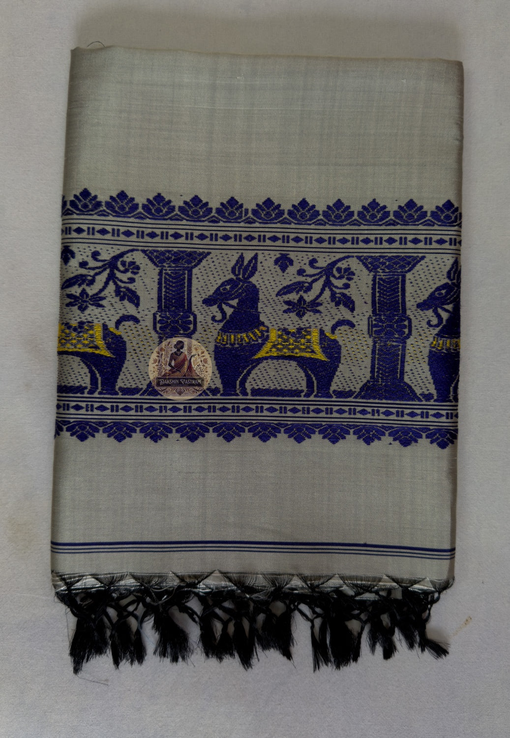 Full flat lay of handwoven Baluchari silk stole in stone grey – complete view of buti body, royal blue court narrative border and black silk tassel fringe, Bishnupur Bengal weave